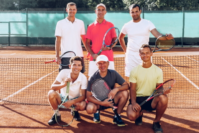 Group portrait of six male tennis players standing on court